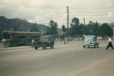 two cars and a streetcar on the road